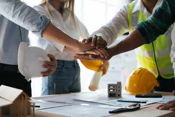 Construction workers, architects and engineers shake hands after completing an agreement in an...