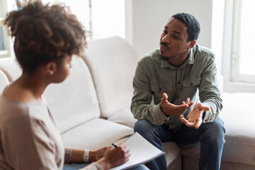 Confused black guy sharing thoughts with psychologist