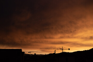 Fototapeta na wymiar La foto mostra lo skyline di una cittadina italiana dopo una tempesta, con i colori del cielo che dominano di arancione e giallo. 