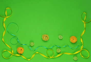 A border with wavy green and yellow ribbons and rattan balls on lime background. Top view, flat...