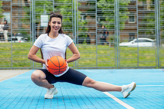 Smiling sportswoman with basketball on background of blue sports court. Sport and hobby concept.