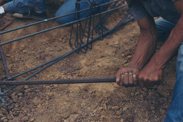 Worker ties wire metal steel to building structure at construction site. Man hand holding material Metal Steel reinforced rod for concrete