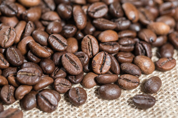 Roasted coffee beans close-up on a burlap background, texture. Good mood. Coffee aroma. Selective focus