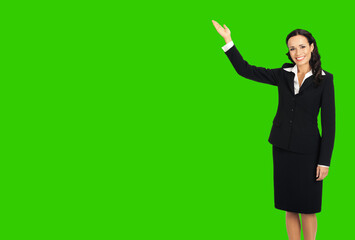 Full body of happy smiling attractive woman in black confident suit, showing copy space. Business concept. Brunette businesswoman. Green chroma key background.