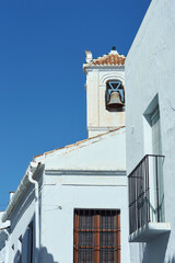 White houses of a village street with a bell tower and clear blue sky