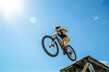 Fototapeta na wymiar girl rider drops downhill in background blue sky