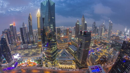 Naklejka na ściany i meble Panorama of futuristic skyscrapers after sunset in financial district business center in Dubai day to night