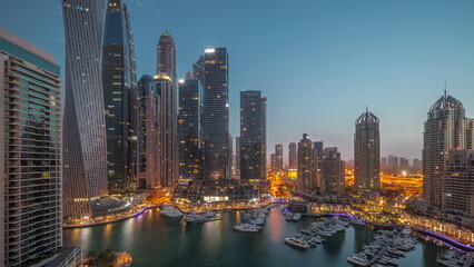 Dubai marina tallest skyscrapers and yachts in harbor aerial night to day .