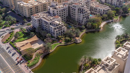 Pond with fountain and low rise buildings in Greens district aerial . Dubai skyline