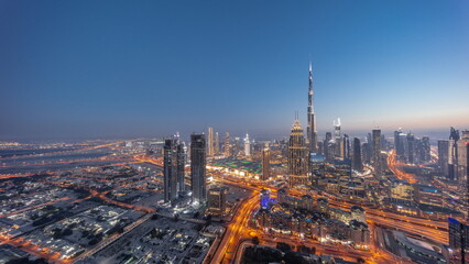 Aerial view of tallest towers in Dubai Downtown skyline and highway day to night .