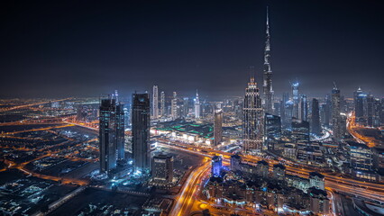 Panorama showing aerial view of tallest towers in Dubai Downtown skyline and highway night .