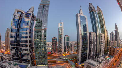 Aerial view of Dubai International Financial District with many skyscrapers night to day .