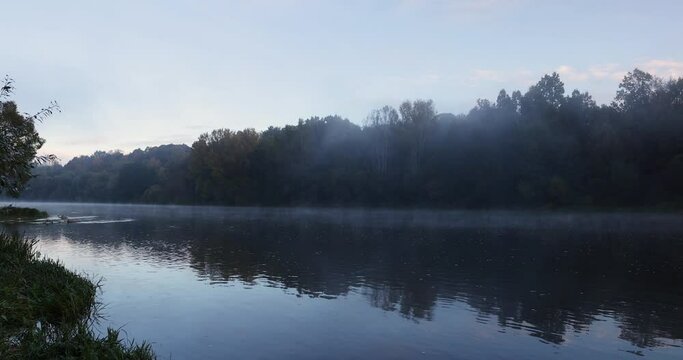 Sunrise in autumn on the river in fog, forest and river during fog