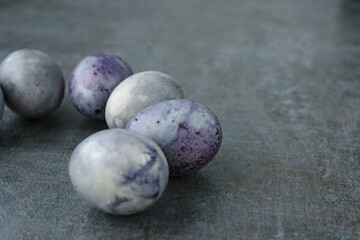 Cosmic-colored painted Easter eggs laid out on dark textural background. Easter concept in minimalist style. Selective focus