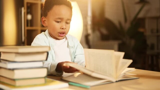 Close up portrait of cute little african american boy hold book and try to make homework while talk with his mother at home Adorable child kid prepares for school with developmental textbooks indoors