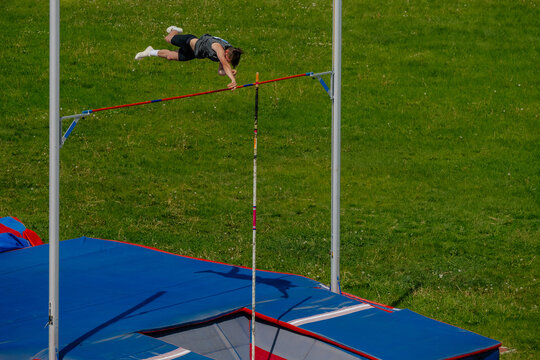 male athlete pole vault on background of green field