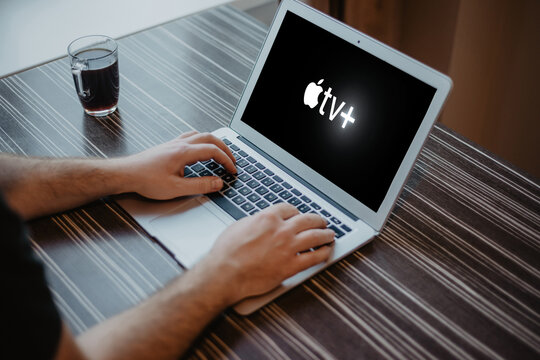 Riga, Latvia - January 31, 2023: Man watching television at home on laptop, Apple TV logo on the screen.