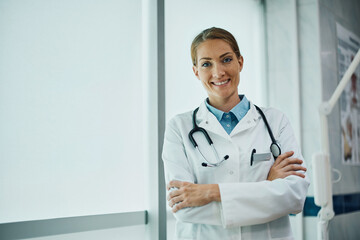 Happy medical expert with her arms crossed at clinic looking at camera.