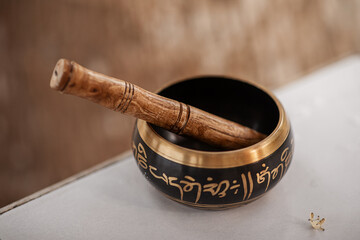 singing Tibetan bowl on the background of the trunk of a palm tree. Relaxation and meditation. Sound therapy. Text interpretation of the mantra: O pearl shining in a lotus flower. Selective focus