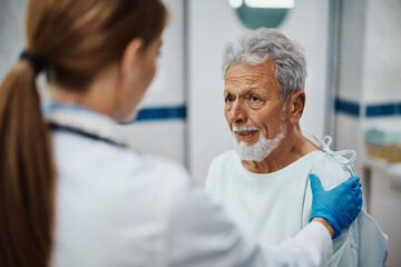 Fototapeta premium Worried senior man getting comforted by doctor at medical clinic.