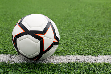 Fototapeta na wymiar New soccer ball on green football field, space for text