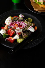 Close up of Greek salad on black plate healthy food fresh vegetables