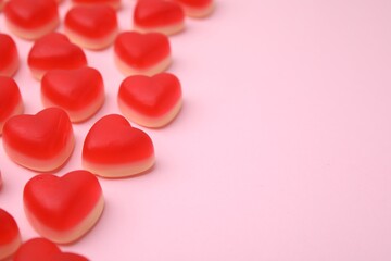 Delicious heart shaped jelly candies on pink background, closeup. Space for text