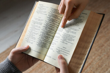 Naklejka premium Woman showing psalm in Bible to man indoors, closeup