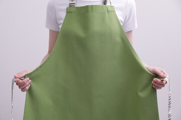 Woman putting on green apron against white background, closeup