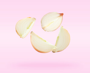 Fresh raw onion slices falling on light pink background