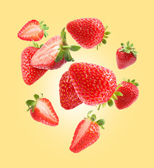 Delicious sweet strawberries falling on pale yellow background