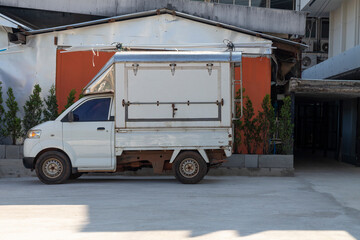 A small white truck parked on the slope outside the building.