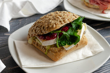 Sandwich with Camembert and lettuce leaves and cranberries.