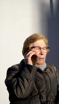 Senior caucasian woman talking on phone outdoors.
