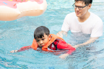 Fototapeta na wymiar Father teaching son to swim at swimming pool. family outdoor activity on holiday in summer weather