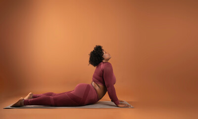 body positive curvy black girl wearing sportswear in studio doing yoga and exercising - obrazy, fototapety, plakaty
