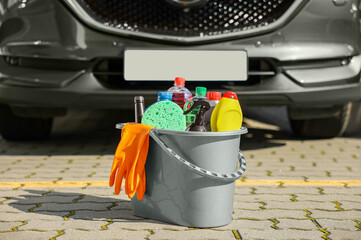 Car cleaning products in bucket near automobile outdoors on sunny day © New Africa