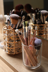 Set of professional makeup brushes near mirror on wooden table, closeup