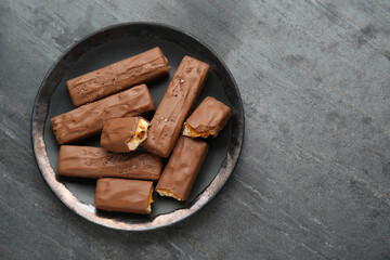 Plate with delicious chocolate bars on black table, top view. Space for text