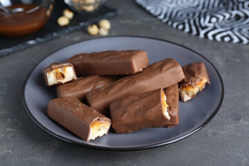 Tasty chocolate bars with caramel and nuts on grey table