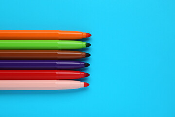 Many different colorful markers on light blue background, flat lay. Space for text