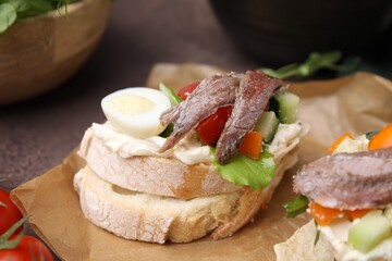 Delicious bruschettas with anchovies, eggs, cream cheese, tomatoes, bell peppers and cucumbers on table, closeup