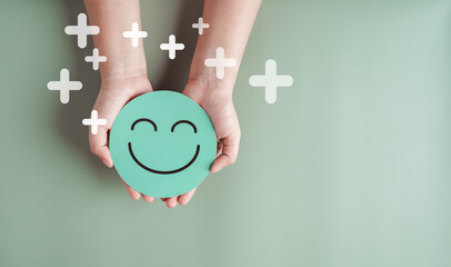 Hands holding green happy smile face, good feedback rating, positive customer review, experience,...
