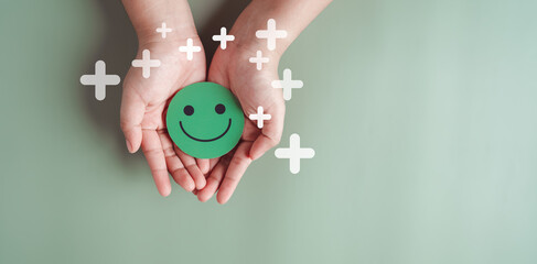 Hands holding green happy smile face, good feedback rating, positive customer review, experience, satisfaction survey, smiley mental health, child wellness, world mental health day on green background - obrazy, fototapety, plakaty