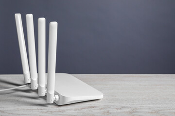 New stylish Wi-Fi router on white wooden table. Space for text