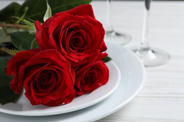 Beautiful place setting with dishware and roses for romantic dinner on white wooden table, closeup