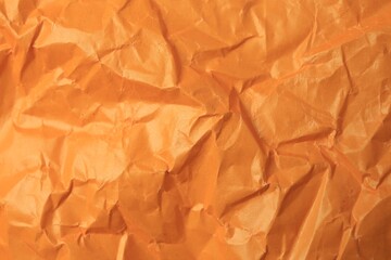 Sheet of crumpled orange paper as background, top view