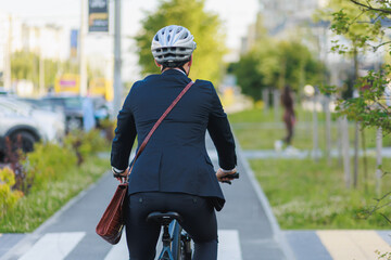 Elegant executive with briefcase getting to work by bicycle on bikeway.