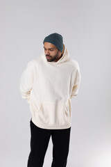 African American man in a knitted hat and white oversized hoodie.