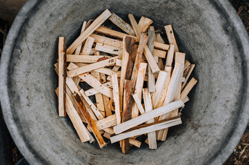 Chopped, sawn boards, firewood lie in a metal tank. Photo, texture, top view.
